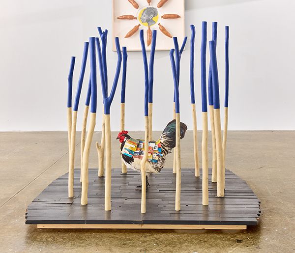 Sculpture of a rooster inside a cage-like structure